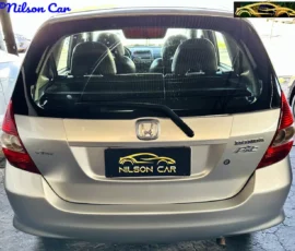 Rear view of a silver Honda Fit with Nilson Car license plate and dealership logos visible on the plate and image corners