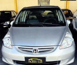 Front view of a silver Honda hatchback at a car dealership, with a Nilson Car license plate sign visible on the bumper.