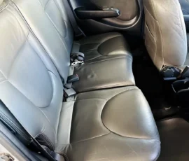 Back seat of a car with black leather upholstery and visible seat belts and headrests.
