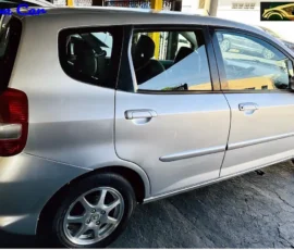 Silver hatchback car photographed from the rear-left, parked on a cracked pavement, with a 'Nilson Car' watermark in the top-left corner.