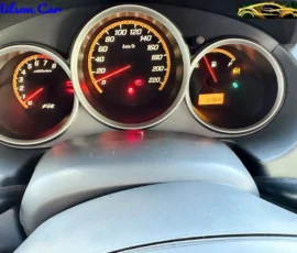Car dashboard instrument cluster with speedometer up to 220 km/h, tachometer, fuel gauge, and warning lights.