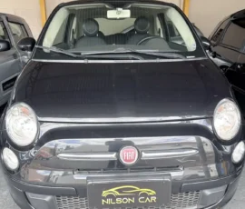 Front view of a black Fiat hatchback in a showroom, Fiat emblem on the grille and Nilson Car plate visible below the bumper.