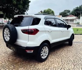 White SUV parked on a cobblestone driveway, with a spare tire mounted on the rear door and tinted rear windows.