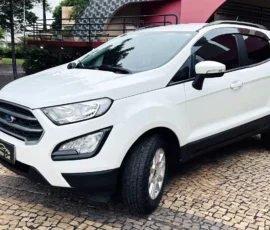 White compact SUV parked on a patterned cobblestone driveway, front three-quarter view showing the Ford emblem and black lower trim.