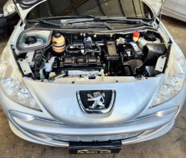 Front view of a silver Peugeot with hood open, showing the car engine bay and surrounding components