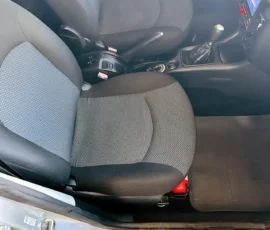 Interior of a car showing the front seats (gray fabric), manual gear shift, center console with controls, and a touchscreen infotainment display on the dash.