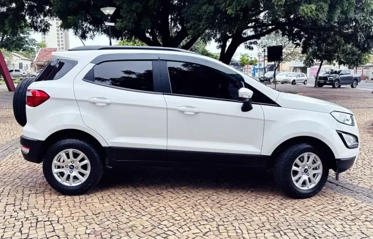 White compact SUV with a mounted spare tire on the rear, parked on a patterned cobblestone surface with dark tinted windows.