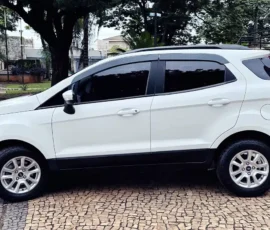 White compact SUV parked on a cobblestone plaza, with a rear-mounted spare tire and black trim along the bottom edge, outdoors in a park setting.