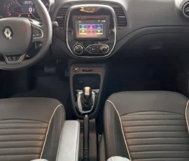 Front interior of a car: steering wheel with Renault logo, digital instrument cluster, and a center touchscreen display above the gear shifter.