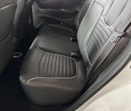 Back seat of a car with black leather seats and light stitching, showing headrests and seat belts.