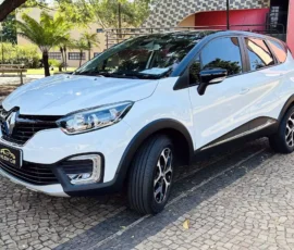 White Renault crossover/SUV parked on a cobblestone lot, front three-quarter view showing headlights, black trim, and roof rails.