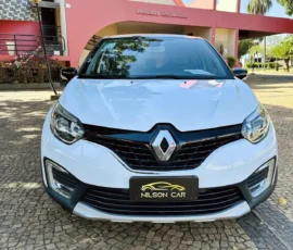 Front view of a white Renault car parked on a cobblestone driveway with a Nilson Car plate.