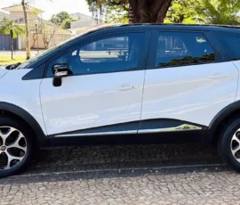 Side view of a white compact SUV parked on a cobblestone street on a sunny day, with black trim and alloy wheels.