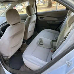 Área dos passageiros traseiros de um carro cinza com bancos de tecido, mostrando o banco traseiro, os bancos dianteiros, o painel da porta e os tapetes.