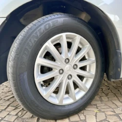 Roda dianteira de um carro com pneu Dunlop e roda de liga leve prateada exibindo uma calota central da Chevrolet.