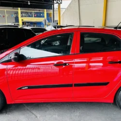 Red Hyundai HB20 hatchback parked at a car dealership lot with other vehicles in the background