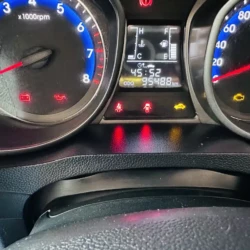 Instrument cluster: tachometer left, speedometer right, central display with warning icons and odometer readout, dashboard indicators lit.