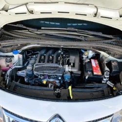 Open hood showing a car engine bay with the battery on the right and various hoses and fluid reservoirs visible.