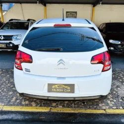 White Citroën C3 seen from the rear in a dealership lot, with other cars parked on either side and a yellow curb in front.