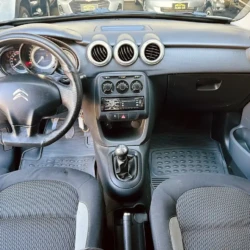 Interior of a car viewed from the back seat showing the steering wheel, dashboard, center console, and two front seats.