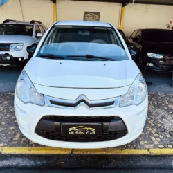 Front view of a white Citroën hatchback parked in a Nilson Car dealership lot with other cars in the background