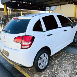 Rear three-quarter view of a white Citroën C3 hatchback parked in a car dealership lot under a canopy