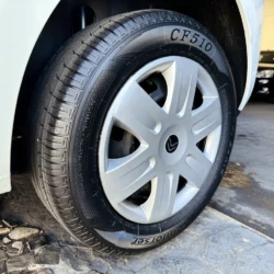 Close-up of a car wheel with a white hubcap and black tire, CF510 visible on the tread, in a dealership lot nearby other cars.