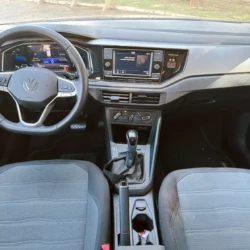 Interior of a VW car showing the steering wheel, digital instrument cluster, center touchscreen, and gear shifter between the front seats