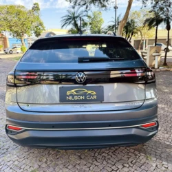 Rear view of a silver Volkswagen Nivus SUV with Nilson Car dealership plate on a cobblestone street.
