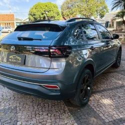 Rear three-quarter view of a gray Volkswagen Nivus SUV parked on a cobblestone street, dealership plate reading Nilson Car.